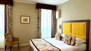 Una habitación de hotel con una cama grande, una silla y un cuadro en la pared.