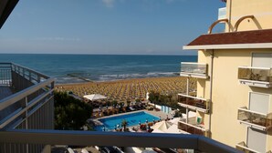 A resort with a pool, beach umbrellas, and a view of the ocean.