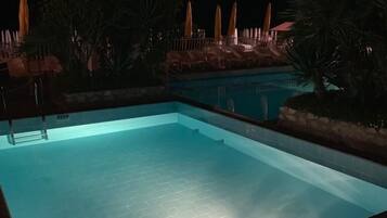 Una piscina al aire libre, sillones reclinables de piscina
