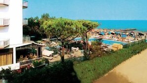 A hotel with a pool area, outdoor seating, and a view of the sea.