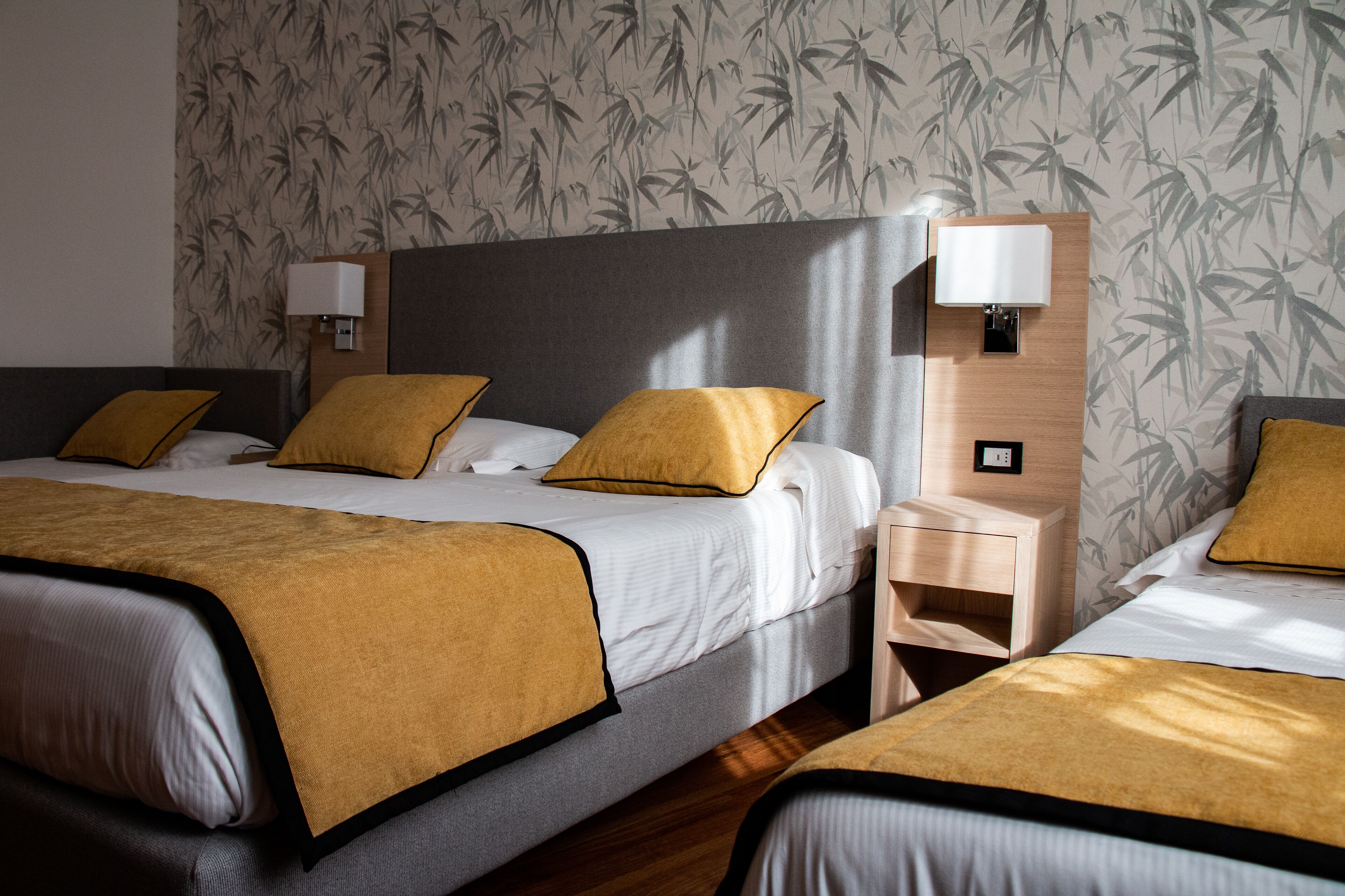 A hotel room with a large bed, two bedside tables, and a wall with a bamboo pattern.