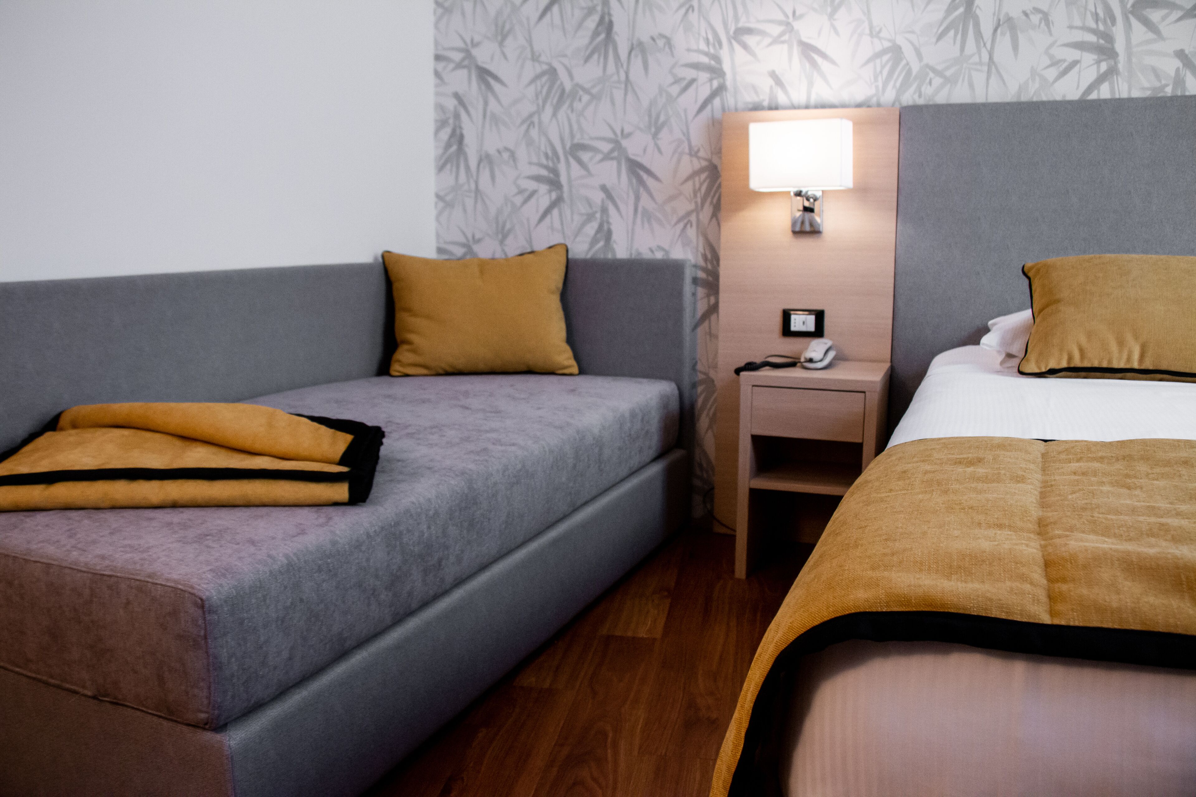 Una habitación de hotel con sofá, cama, mesita de noche y lámpara.