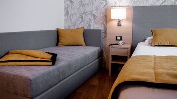 Una habitación de hotel con sofá, cama, mesita de noche y lámpara.