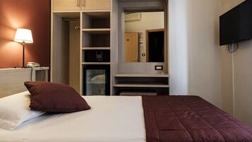 Een hotelkamer met een bed, een kledingkast, een bureau en een televisie.