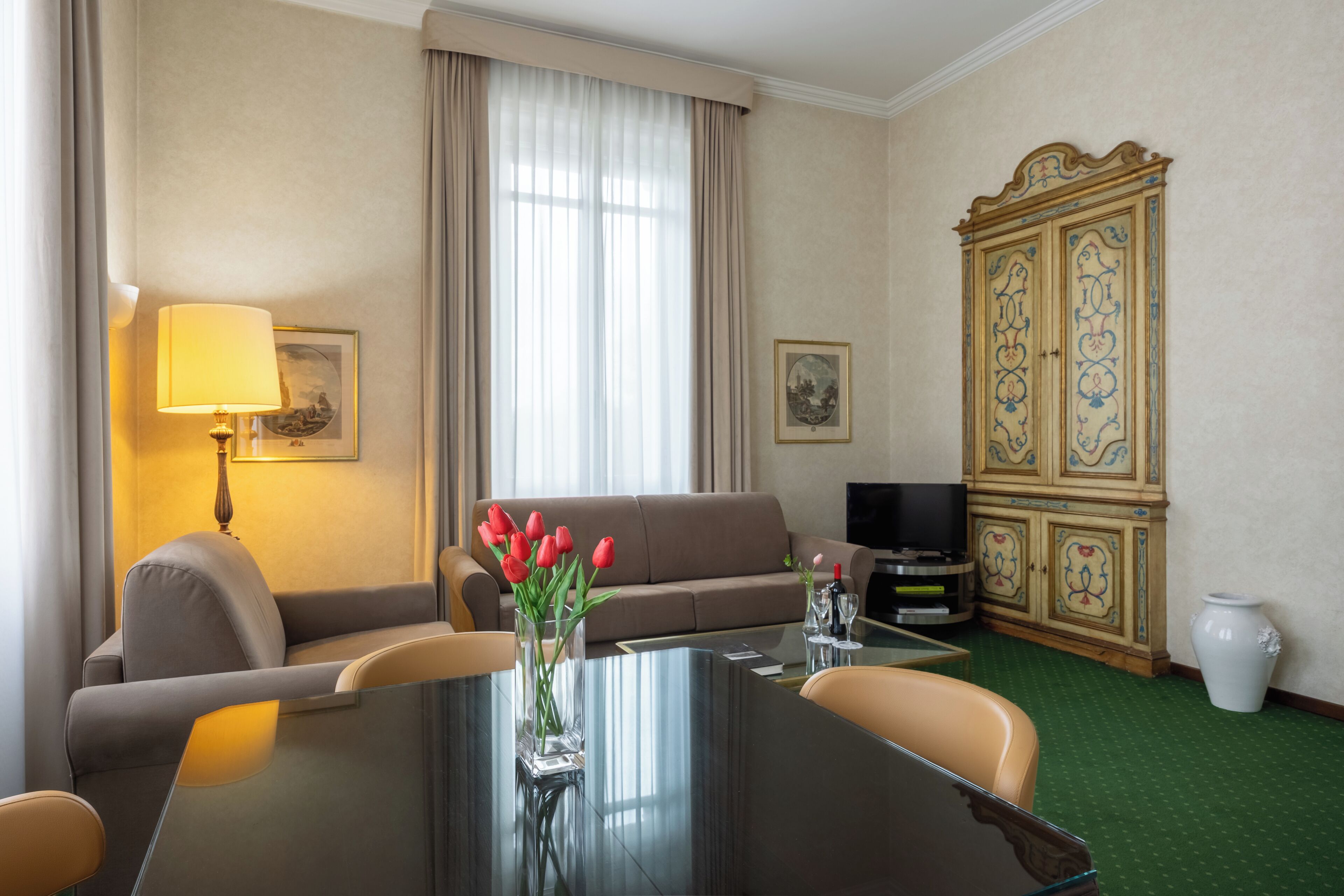 Une chambre d’hôtel équipée d’une table à manger, d’un canapé, d’une télévision et d’un meuble décoratif.