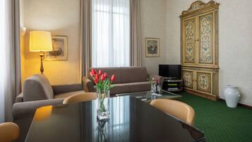 Une chambre d’hôtel équipée d’une table à manger, d’un canapé, d’une télévision et d’un meuble décoratif.