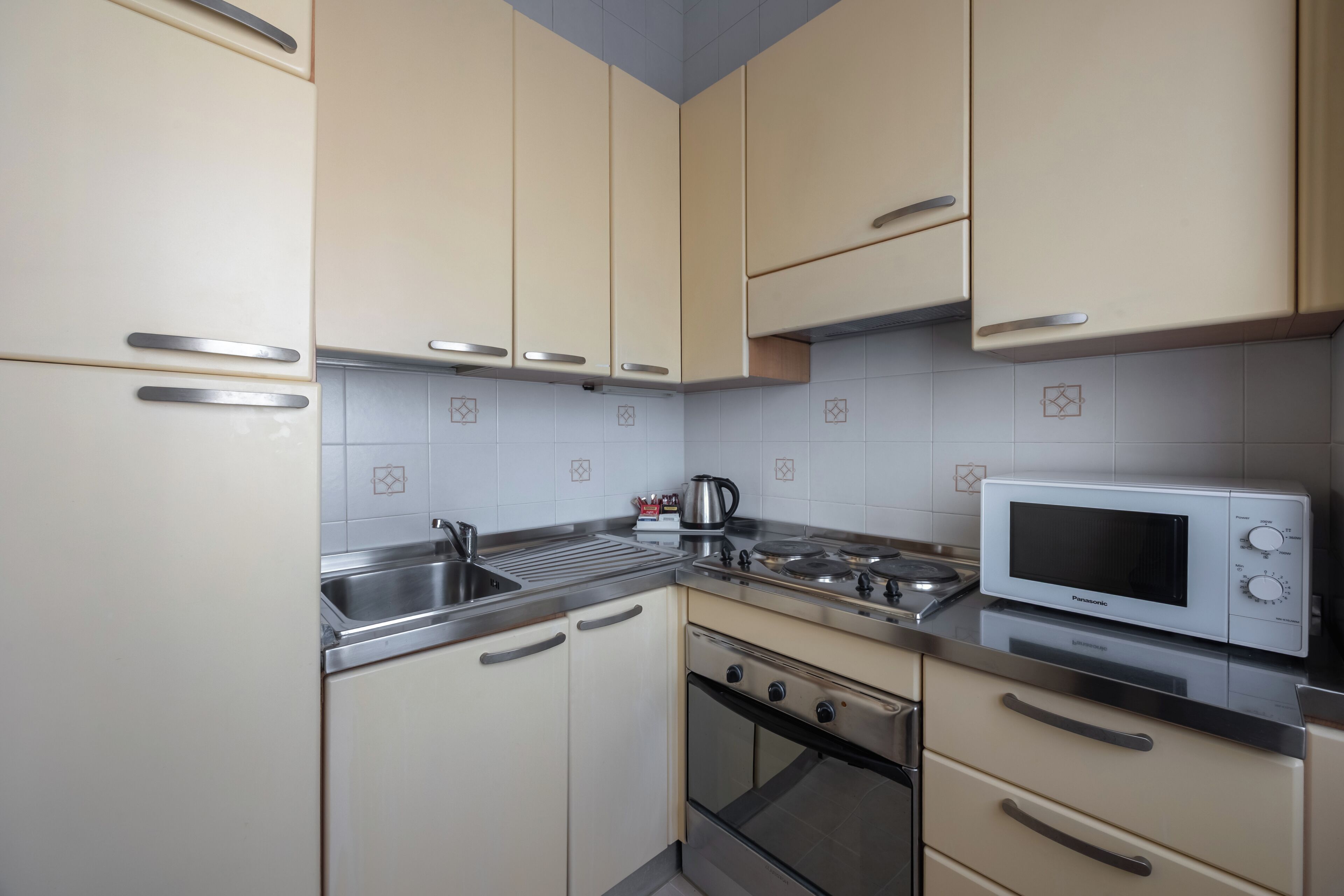 A kitchen with beige cabinets, stainless steel appliances, and a microwave.