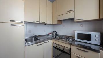 A kitchen with beige cabinets, stainless steel appliances, and a microwave.