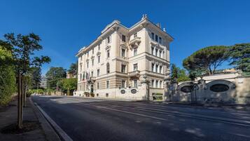 A multi-story building with classical architecture, a wide street, and a clear blue sky.