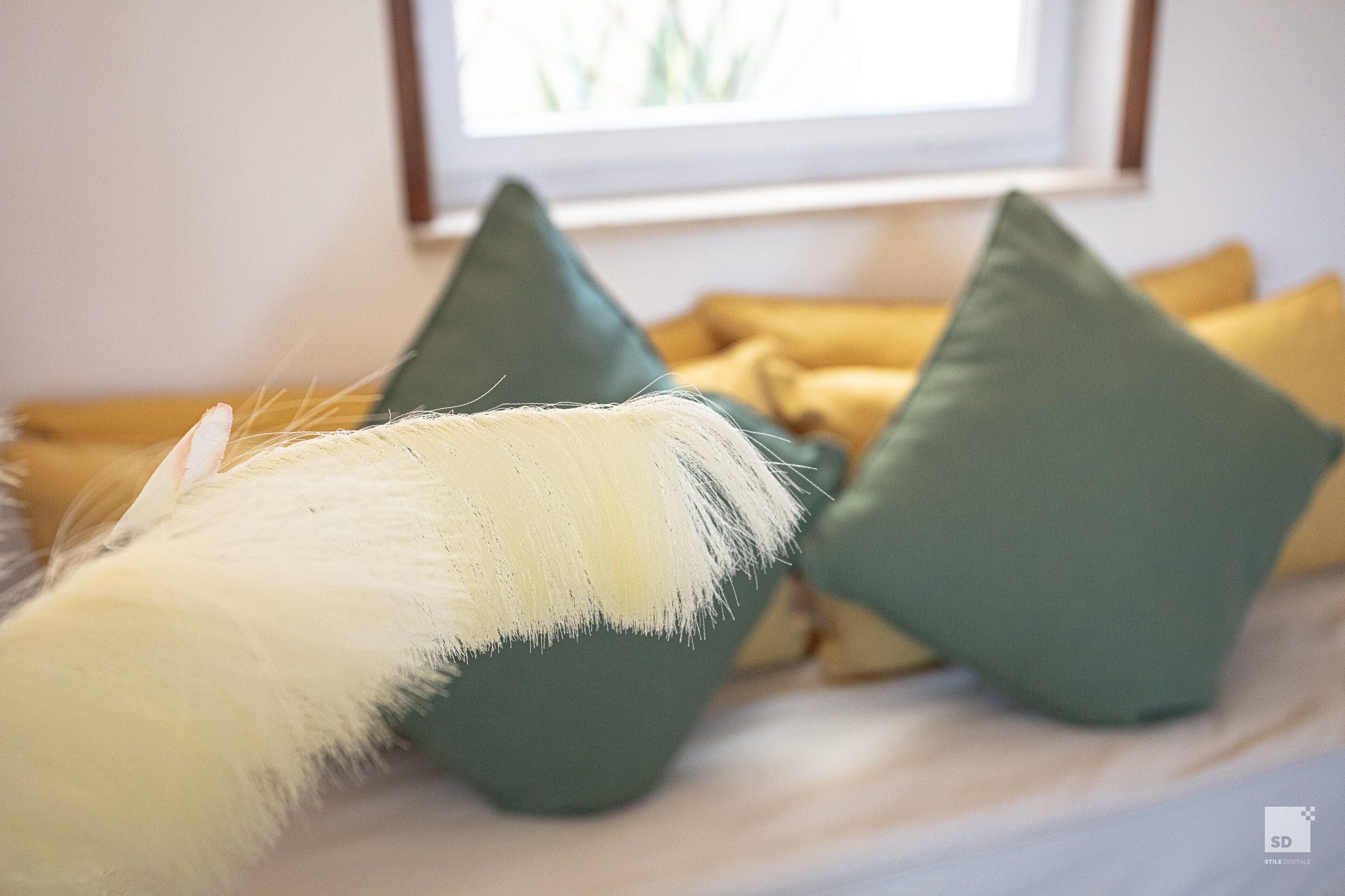 Een bed met kussens in groen en geel.