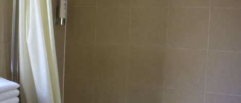 A bathroom with a bathtub, a shower curtain, and beige tiled walls.