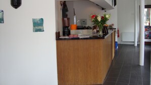 A kitchen with a wooden counter, a coffee machine, and a vase with flowers. - Islington Inn (London)