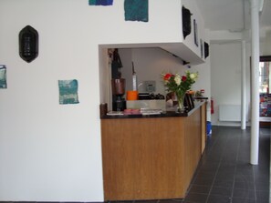 Uma cozinha com bancada de madeira, cafeteira e um vaso com flores.