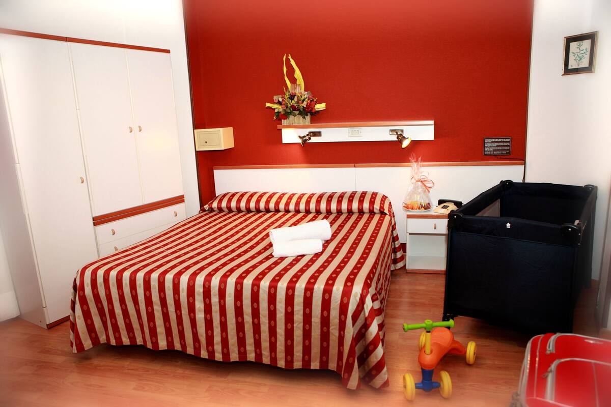 A hotel room with a bed, a desk, a chair, and a toy car.