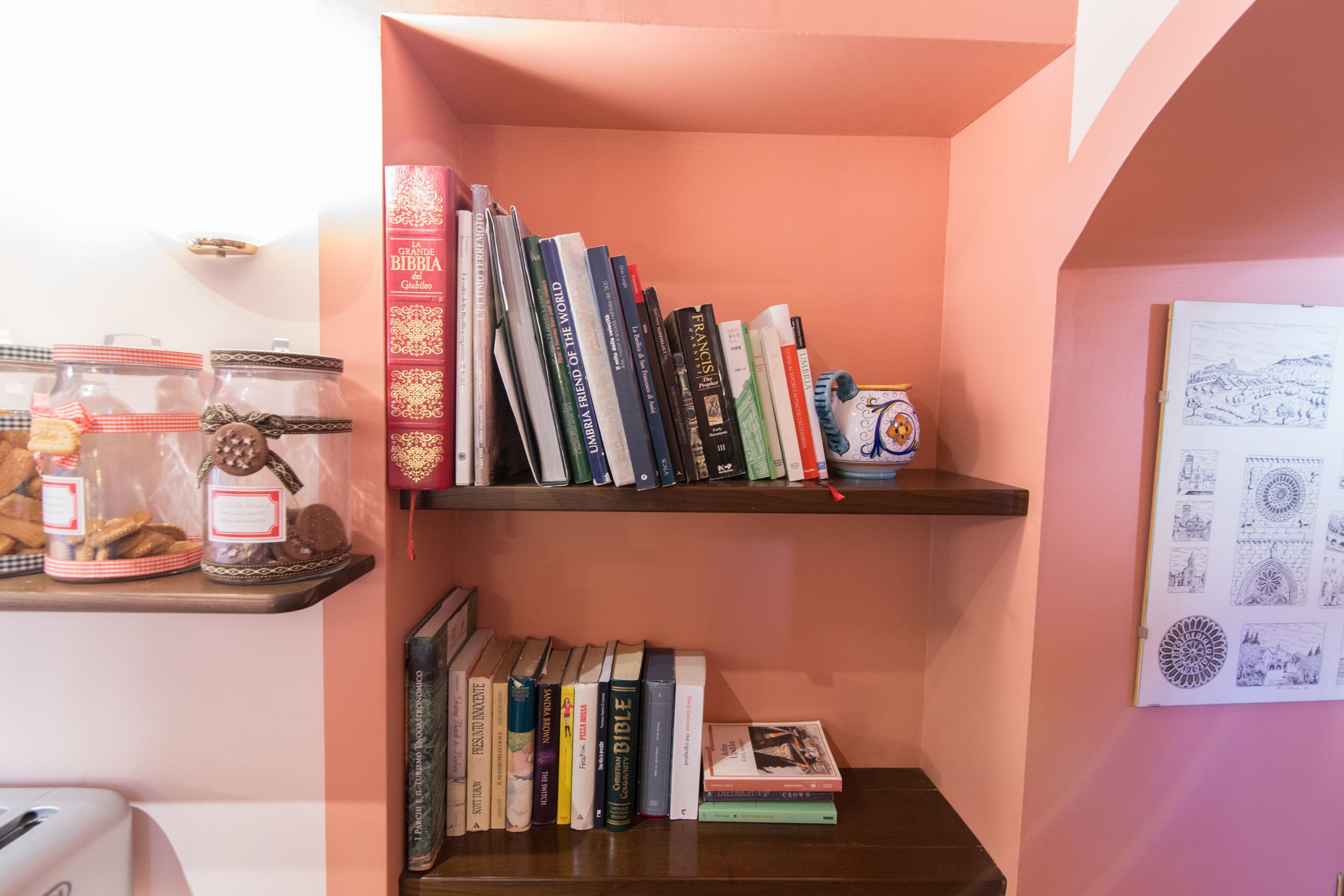 A bookshelf with various books and jars of cookies.