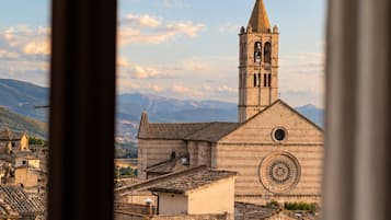 A view of a church with a bell tower and a circular window through a window frame.