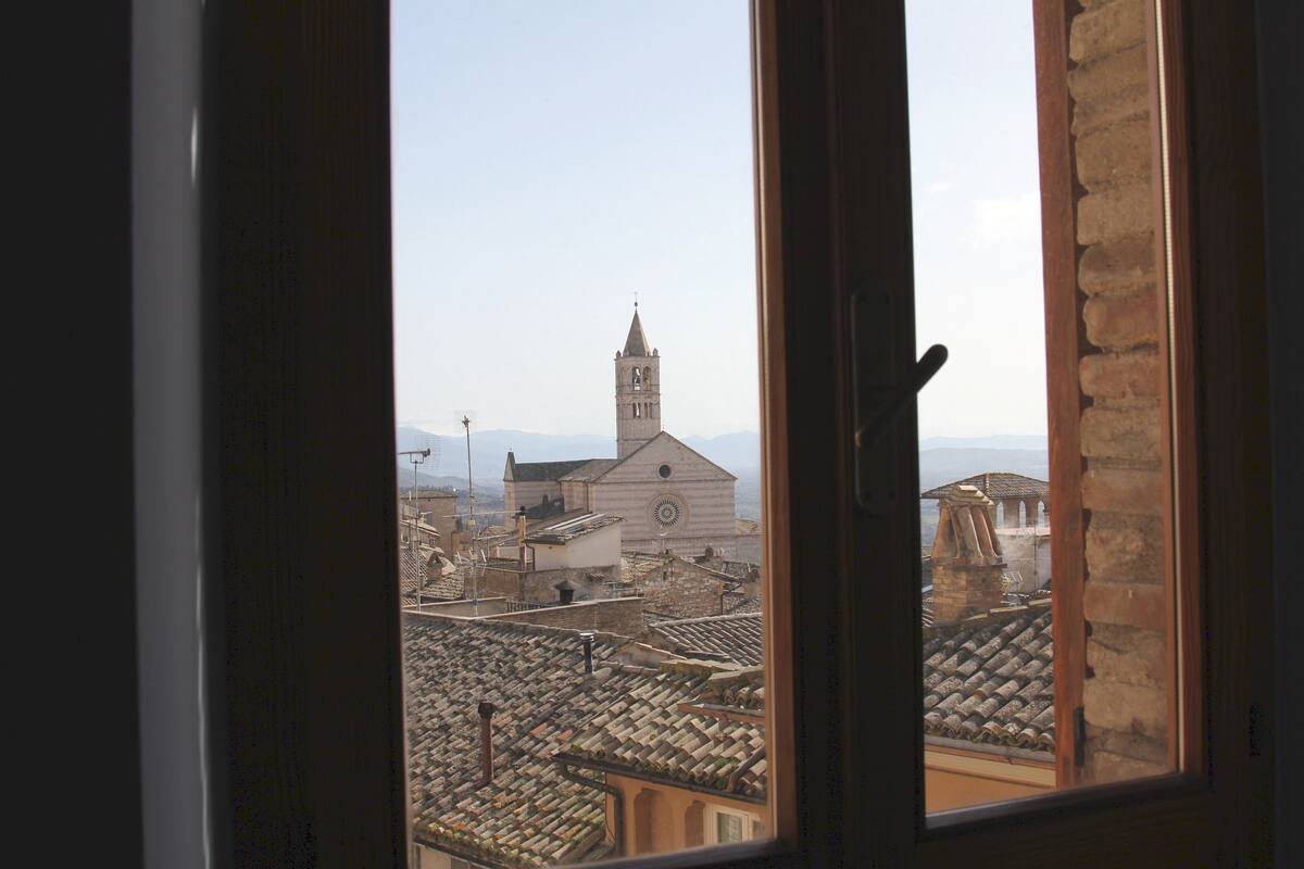 A view through a window of a building with a bell tower and a church in the background.