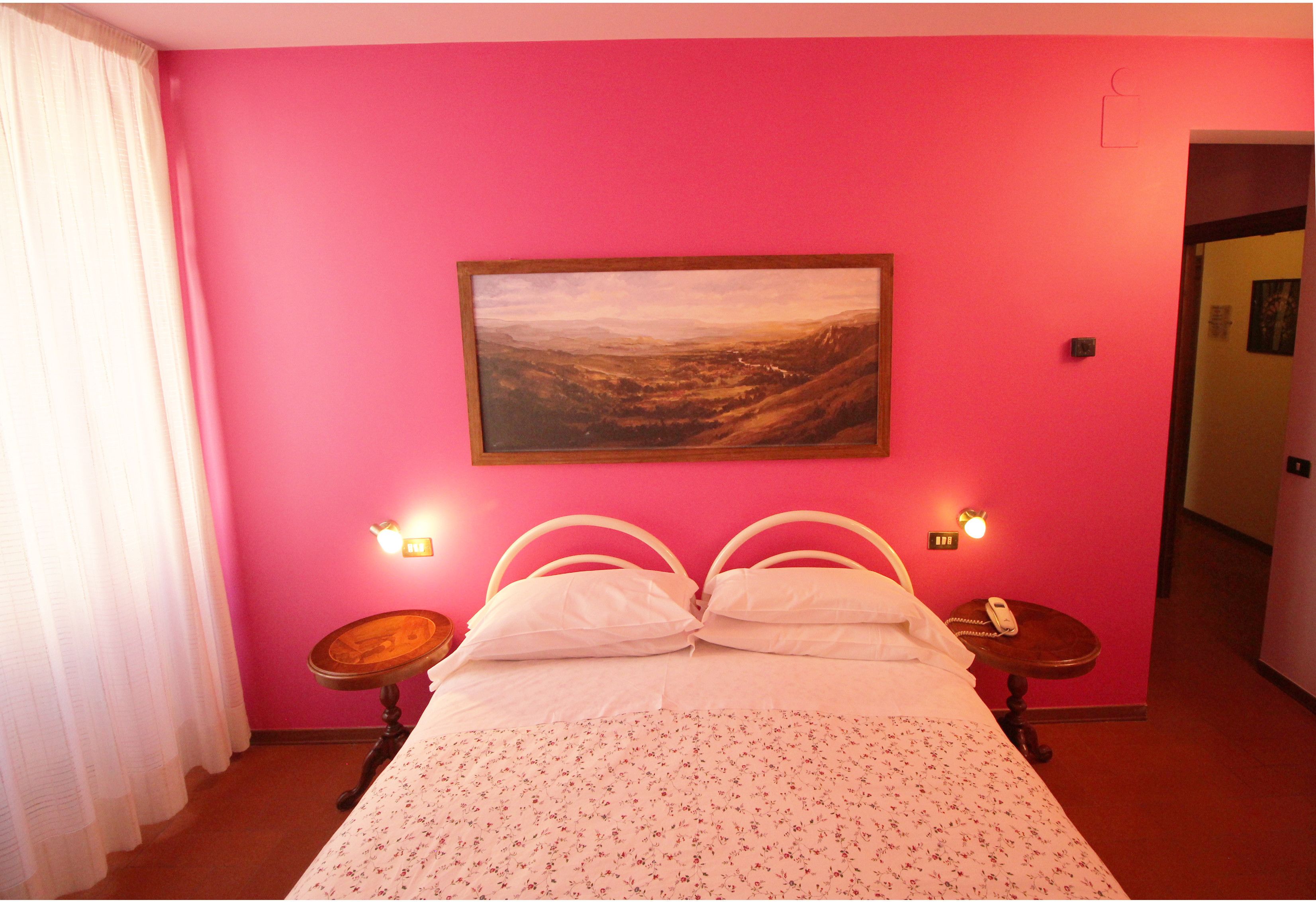 Una habitación con una cama, un cuadro en la pared y dos mesitas de noche con lámparas.