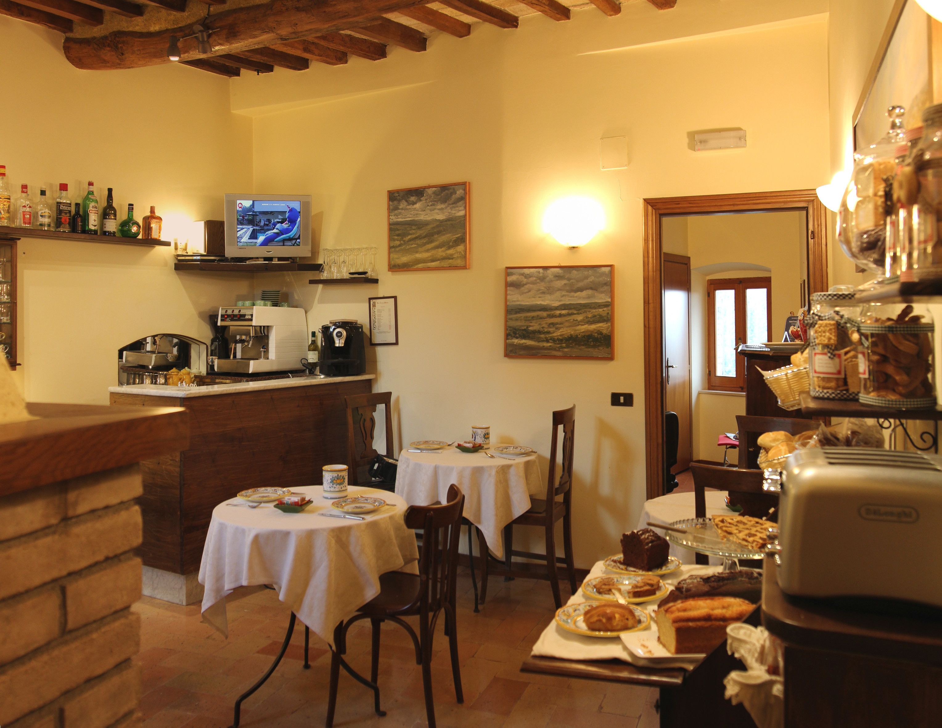 A cozy dining area with a kitchen in the background, a television, and various food items displayed.