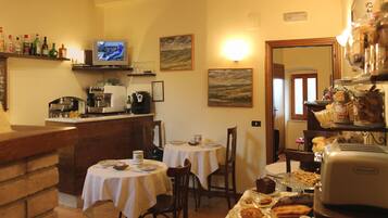 A cozy dining area with a kitchen in the background, a television, and various food items displayed.