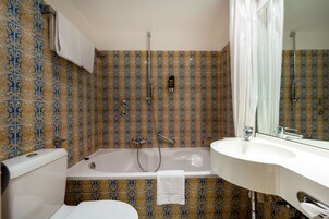 Un bagno con piastrelle decorate, una vasca, un lavandino e un water.