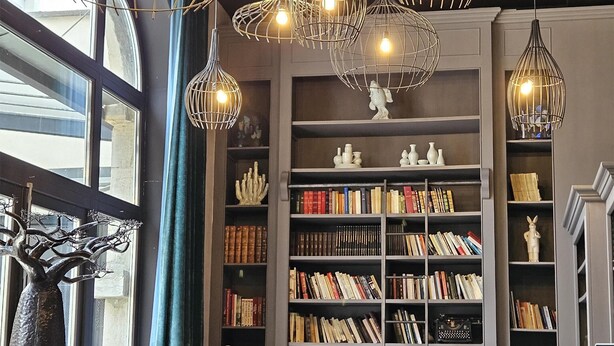 Un rincón acogedor para leer con estanterías, sillones de cuero e iluminación colgante original.
