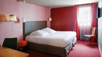Una camera d'albergo con un letto, una scrivania, una sedia e una televisione.