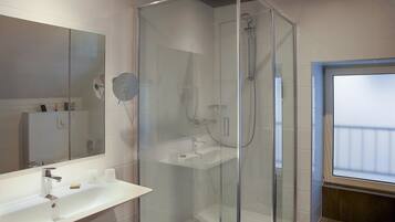 Une salle de bain moderne avec une douche à parois de verre, un lavabo blanc et un grand miroir.