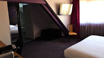 Een hotelkamer met een bed, een stoel, een bureau en een spiegel.