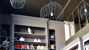 Una biblioteca moderna con asientos de cuero, estanterías y lámparas colgantes esféricas únicas.
