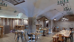 Un restaurante con mesas y sillas de madera, pilares de piedra y lámparas colgantes.