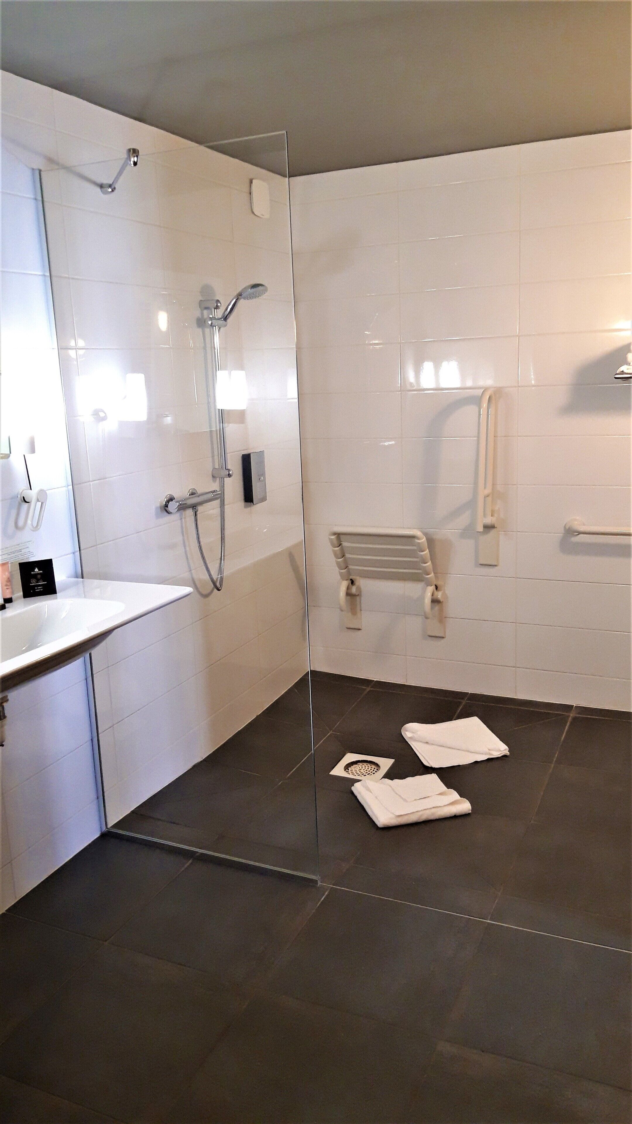 Une salle de bain moderne avec une douche à parois de verre, un lavabo blanc et un porte-serviettes.