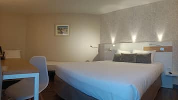 Una habitación de hotel con cama, mesita de noche, lámpara y escritorio con silla.