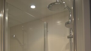 A glass-enclosed shower stall with a handheld showerhead, a towel rack, and a control panel. - Brit Hotel Les Alizés (Pornic)