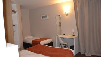 A hotel room with two beds, a desk, a chair, a mirror, and a picture on the wall.