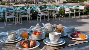A poolside breakfast setup with tables, chairs, and a variety of food and drink items. - Hotel Orient & Pacific (Jesolo)
