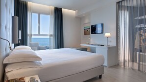 A modern hotel room with a large bed, a desk, and a view of the sea. - Hotel Orient & Pacific (Jesolo)
