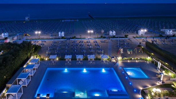A large outdoor swimming pool with adjacent lounge areas and a beach with rows of sunbeds. - Hotel Orient & Pacific (Jesolo)