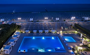 A large outdoor swimming pool with adjacent lounge areas and a beach with rows of sunbeds. - Hotel Orient & Pacific (Jesolo)