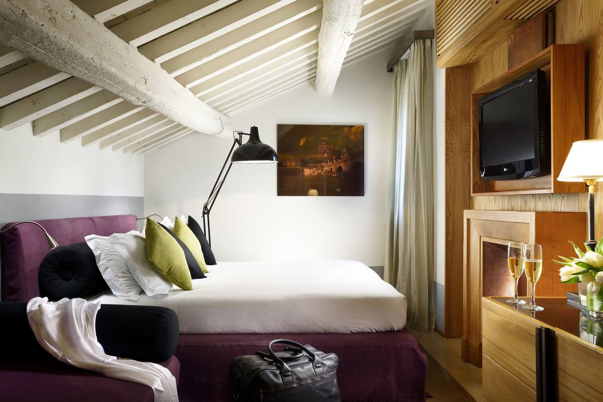 Une chambre d’hôtel avec un lit, un bureau doté d’une lampe, une télévision et un tableau accroché au mur.