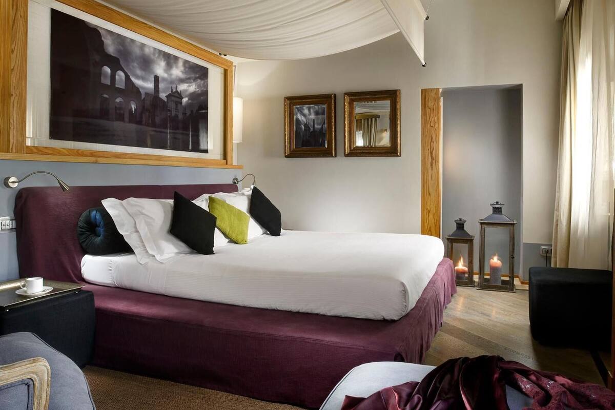 Une chambre d’hôtel avec un grand lit, une table de chevet, une lampe et un tableau au mur.