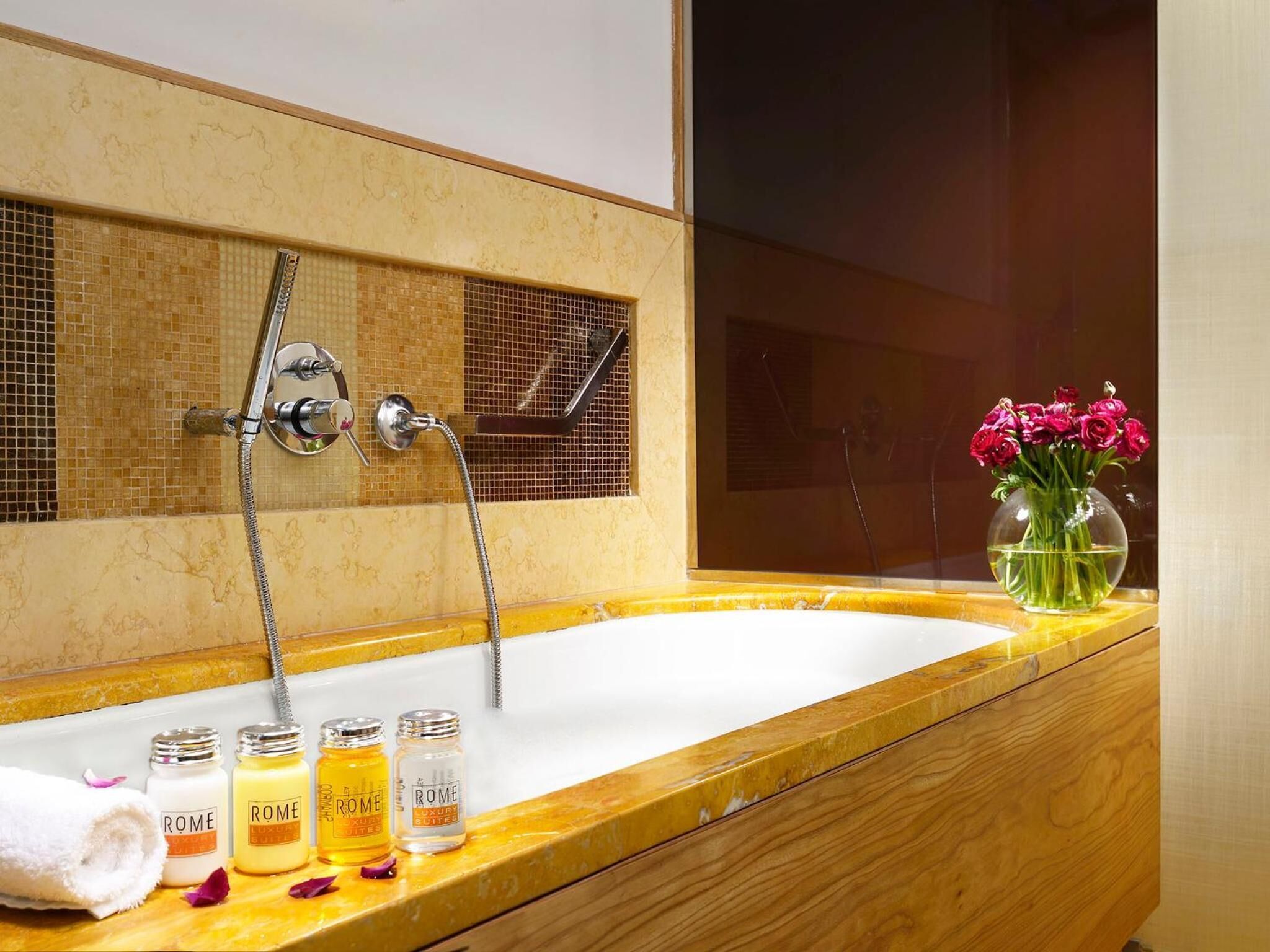 A bathroom with a large mirror, a bathtub, and a vanity with toiletries.