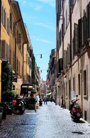 A cobblestone street lined with historic buildings, some with shutters and balconies. - Mario de Fiori 37 (Rome)