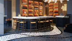 A bar area with a central island, bar stools, and a ceiling fan. - Mario de Fiori 37 (Rome)