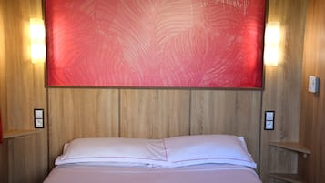 A neatly made bed with white linens and red piping, a large red abstract painting on the wall, and wooden paneling.