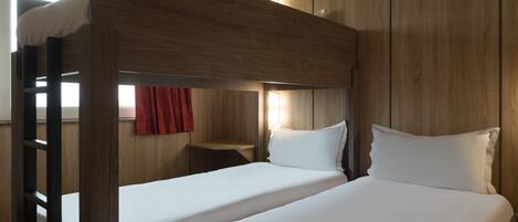 Habitación con literas, paredes de madera y una cortina roja.