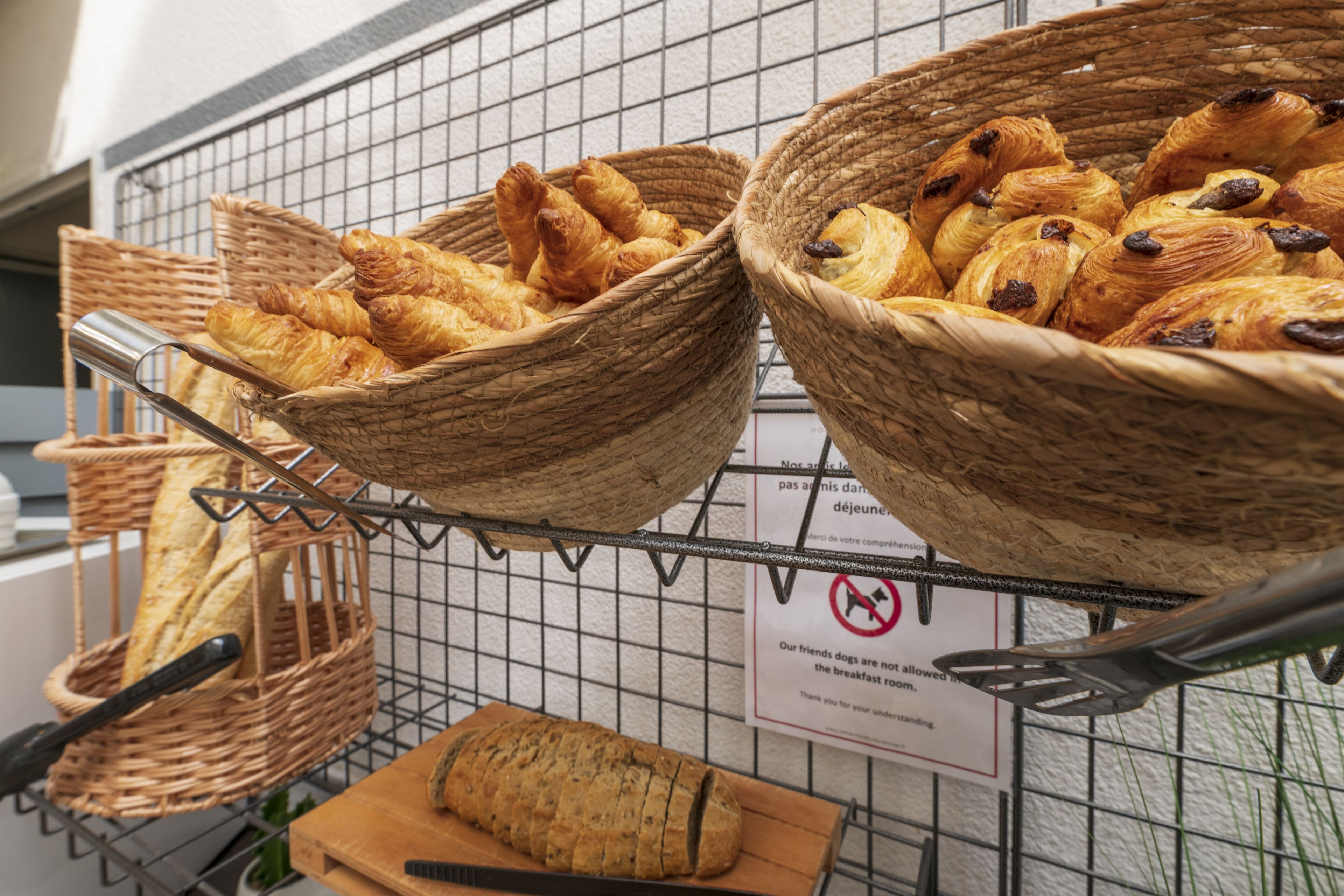 Wicker baskets filled with pastries and a loaf of bread on a rack.