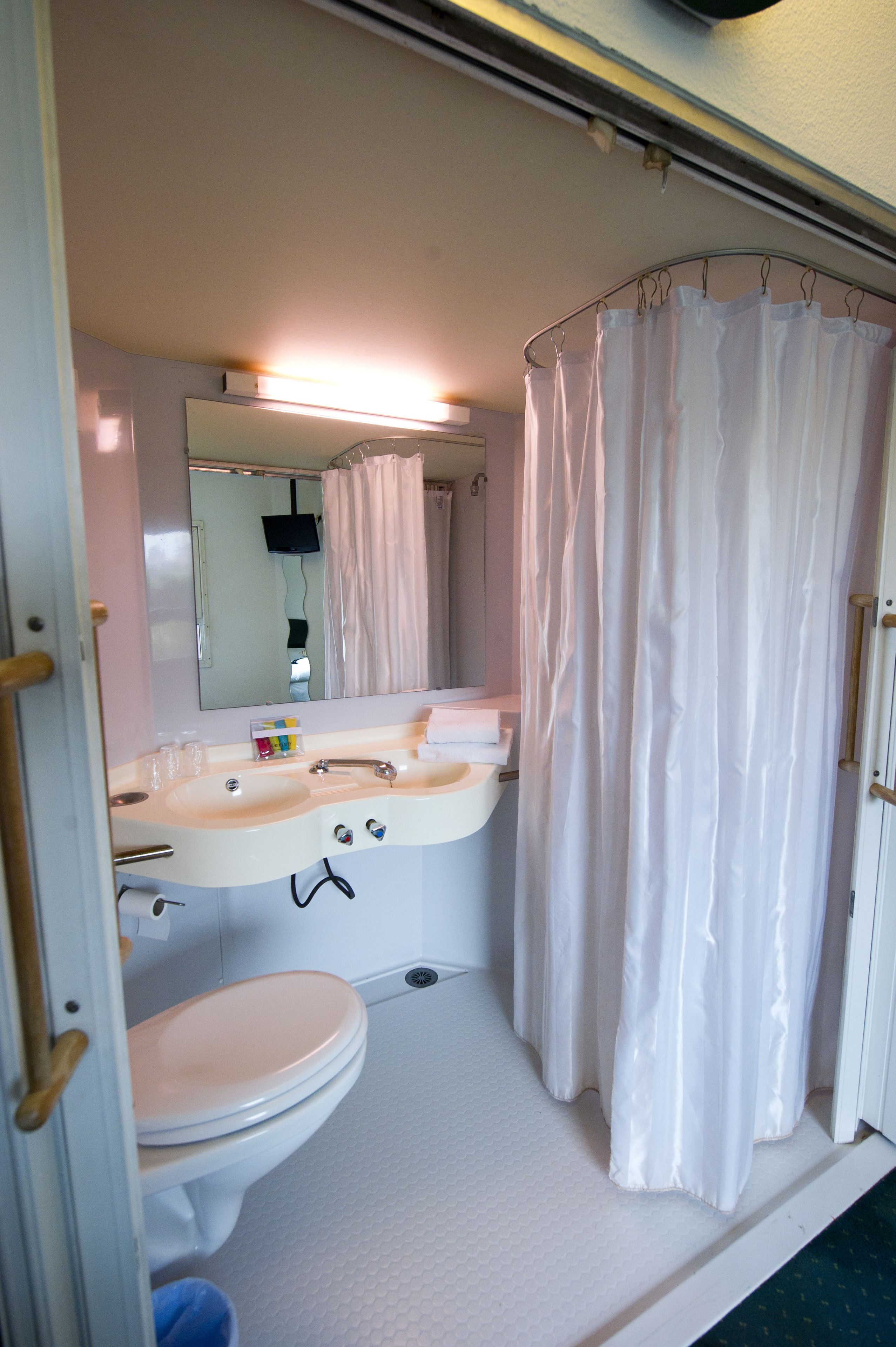 A bathroom with a white sink, mirror, and toilet.