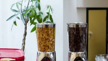 Un buffet de petit-déjeuner proposant une variété d’aliments, notamment du pain, des gâteaux et un distributeur de café.