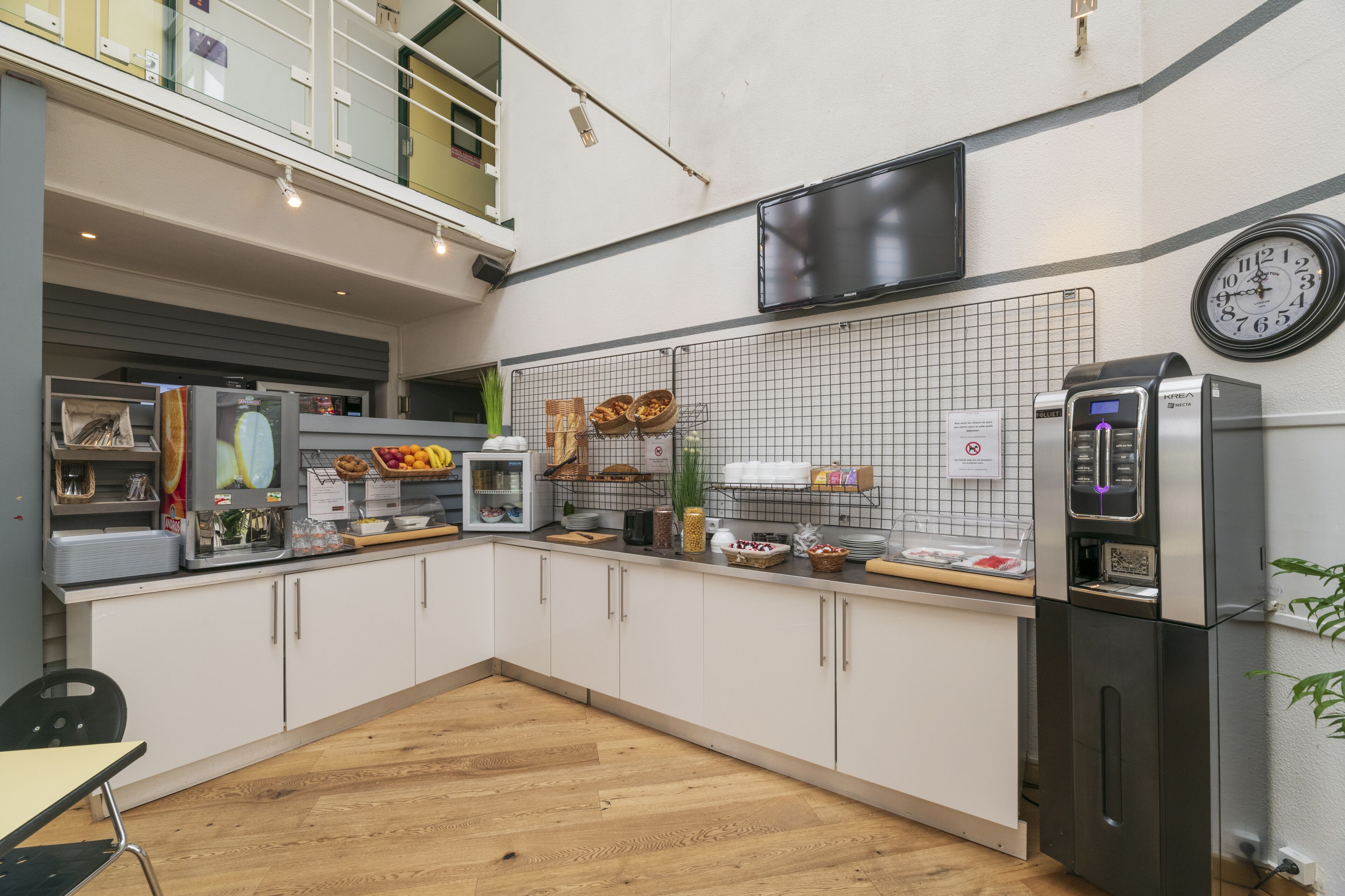 A modern kitchen with white cabinets, a stainless steel refrigerator, a coffee machine, and a variety of food items on the counter.